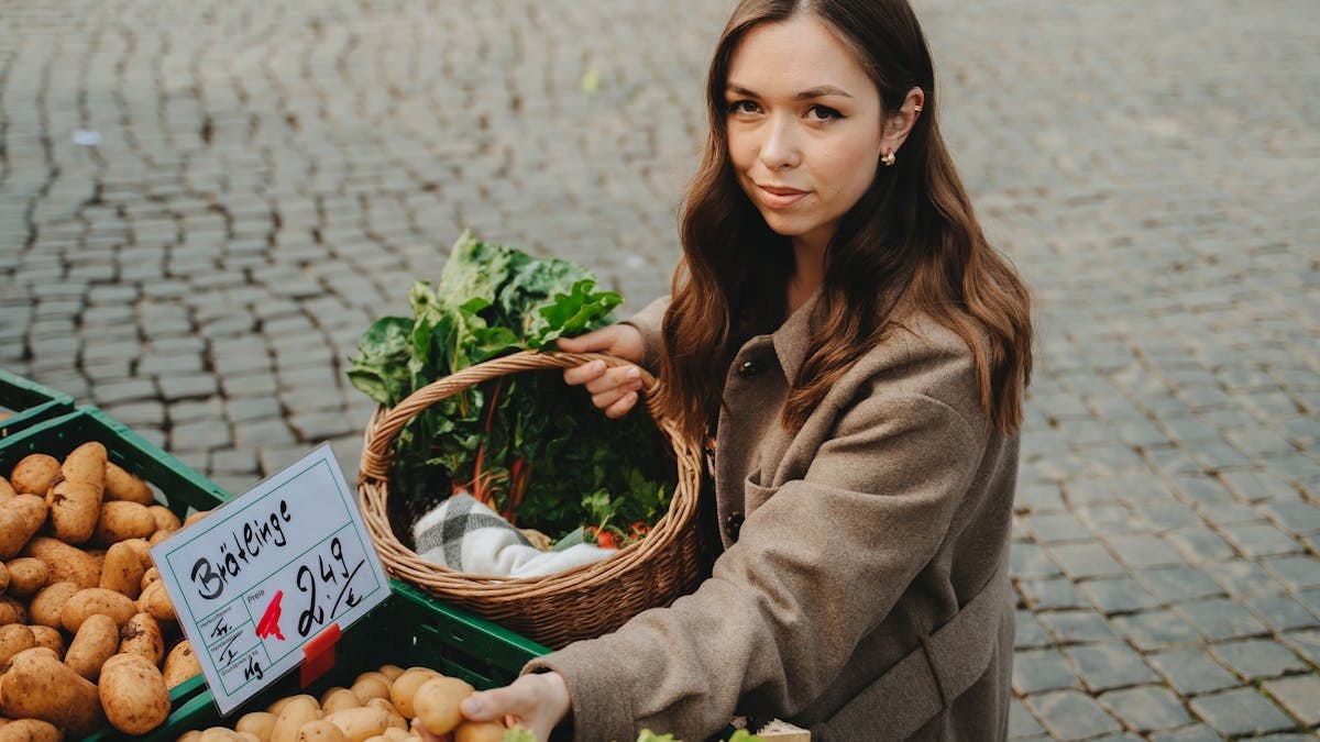 Young woman shopping at Erfurt farmers market, holding basket with fresh vegetables. Capturing local shopping culture.